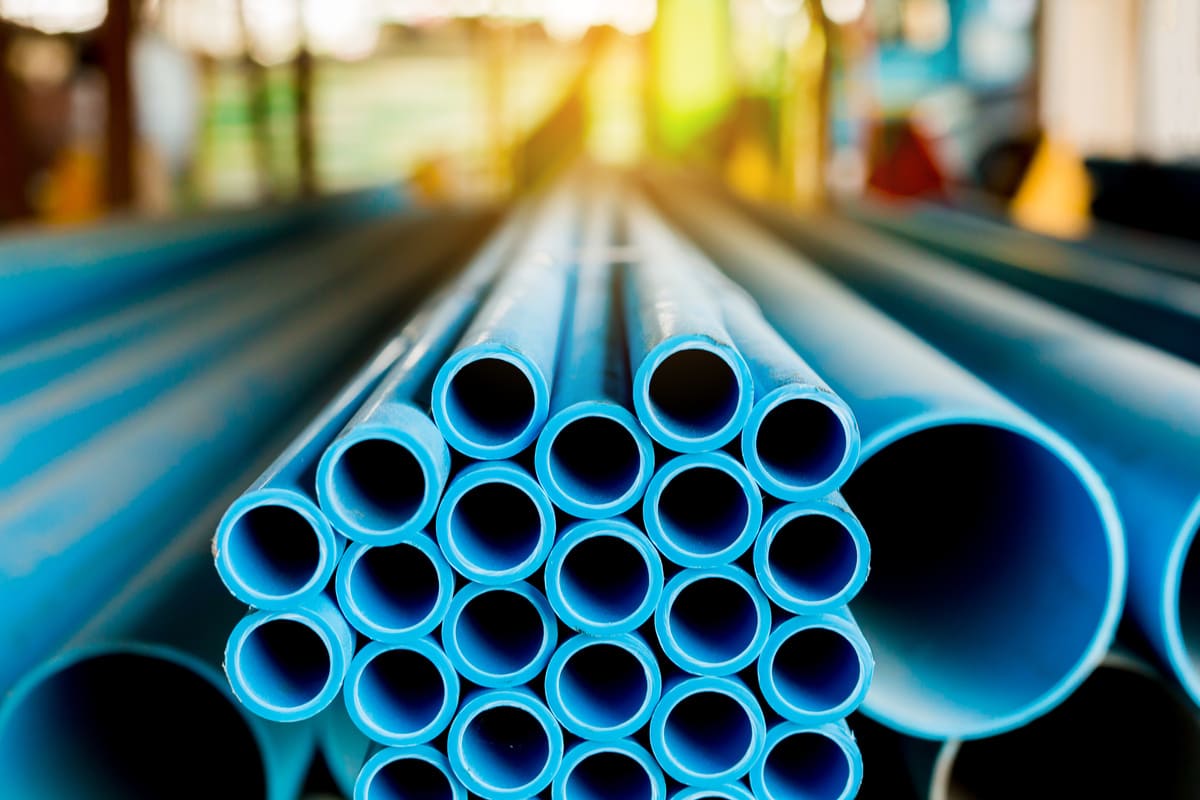 Stacked blue plastic pipes arranged in a warehouse or industrial storage facility.